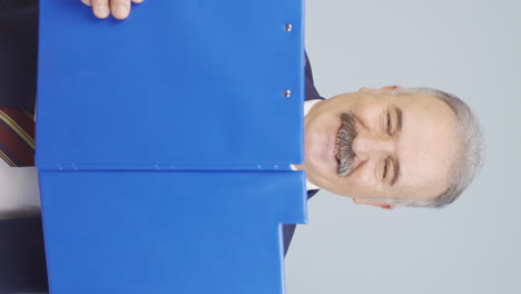 Vertical-video-of-Old-businessman-looking-from-behind-files.